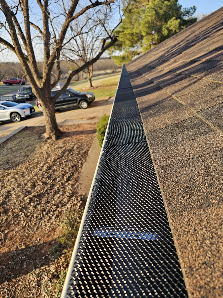 Gutter guard installed along the edge of a shingle roof by Ace Renovations